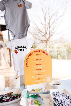 a baby's first birthday party is set up with items like onesie and small fry