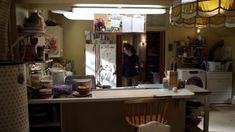 a woman standing in a kitchen next to a stove top oven and refrigerator freezer