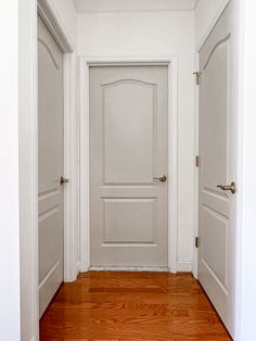 an empty hallway with two doors and hard wood flooring on one side, and another door in the other