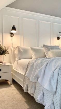 a white bed sitting in a bedroom next to two lamps on either side of it