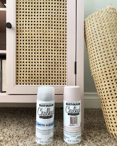 two spray paint cans next to a wicker cabinet