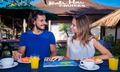 a man and woman sitting at a table with orange juice