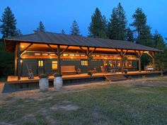 a large wooden building sitting on top of a lush green field next to tall trees