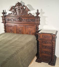 an ornate wooden bed frame next to a night stand