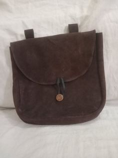 a brown suede purse sitting on top of a bed