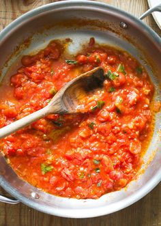 a pan filled with tomato sauce and a wooden spoon