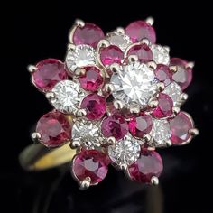 A stunning estate cocktail cluster ring featuring diamonds and rubies with total gemstone weight is just under 4 carats. The diamond in the center is 0.46ct and total diamond weight of the ring is 1.58ct, rubies total weight 2.40ct. The color of the rubies is beautiful and the ring has a great look Gold: hallmarked 18k gold shank, prongs tested 14k gold Gemstones: Diamonds - total diamond weight 1.58ct by formula, the round brilliant cut diamond in the center is approximately 0.46ct by formula, Red Band, Diamond Cluster Ring, Diamond Cluster, Flower Ring, Vintage Diamond, Round Brilliant Cut Diamond, Cluster Ring, Cocktail Ring, Brilliant Cut Diamond