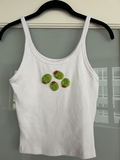 a white shirt with green buttons hanging on a hanger in front of a window