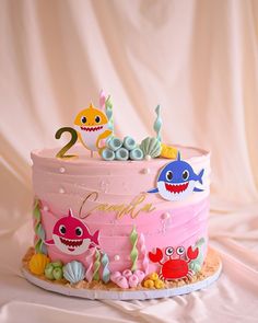 a birthday cake with pink frosting and colorful decorations on the top is decorated with sea animals