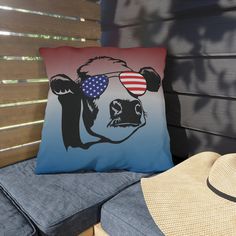 a cow with sunglasses and an american flag on it's face is sitting on a bench