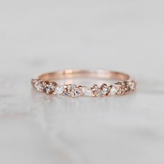 a rose gold wedding band with small diamonds on the inside and outside, sitting on a marble surface