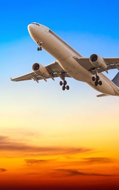 an airplane is flying in the sky at sunset