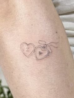 a small tattoo with two hearts on the arm