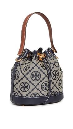 PRICES MAY VARY. Fabric: Jacquard Structured silhouette, Gold-tone hardware, Monogram print Length: 8.25in / 21cm, Height: 8.25in / 21cm, Handle drop: 4in / 10cm, Strap drop: 21.75in / 55cm, Depth: 4.75in / 12cm Drawstring closure Patch interior pocket A scaled-down Tory Burch bucket bag, detailed with a rendition of the label's monogram for a polished and eye-catching look. Two shades of leather trim lend an eclectic finish to the silhouette. Tory Burch Bucket Bag, T Monogram, Mini Bucket Bags, Mini Bucket, Monogram Prints, Tory Burch Miller, Tory Burch Bag, Metallic Logo, Womens Tote Bags