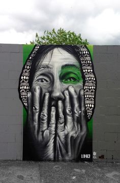 a painting on the side of a building with hands covering it's face and eyes