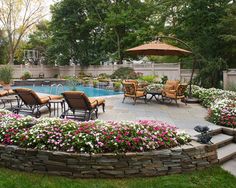 an outdoor patio with chairs and tables next to a swimming pool in the middle of a garden