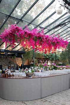 an outdoor bar with pink flowers hanging from the ceiling