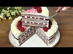 someone is cutting into a cake with white frosting and raspberries