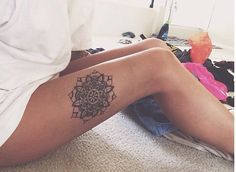 a woman sitting on the floor with her legs crossed and tattoos on her leg,