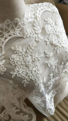 the back of a white dress with flowers on it and lace overlaying it