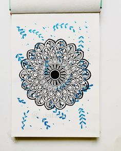 a blue and black flower on white paper hanging from a wall above a pair of scissors