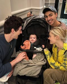 three people sitting next to each other with a baby in a stroller