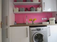 a washer and dryer in a small room with pink painted wall behind it