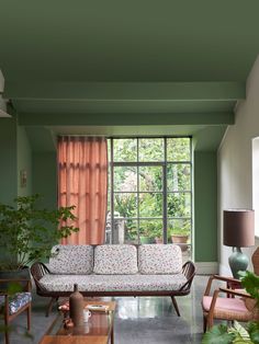 a living room filled with furniture next to a large window and potted plants in front of it