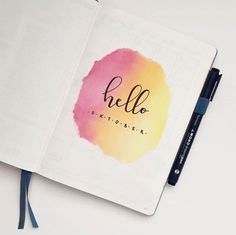 an open notebook with the word hello written on it and a pen next to it