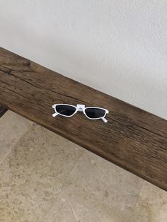 a pair of sunglasses sitting on top of a wooden bench next to a tiled floor