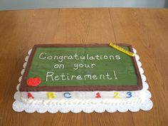 a cake with congratulations written on it sitting on top of a wooden table in front of a chalkboard