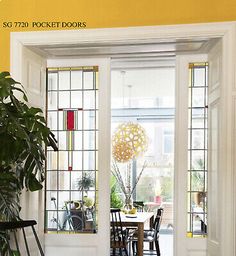 an open door leading to a dining room with yellow walls and white trim on the windows