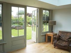 a living room filled with furniture next to a wooden floor covered in glass doors and windows