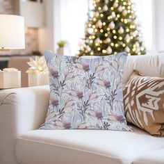 a living room with a christmas tree in the background and pillows on the couches