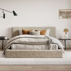 a large bed sitting on top of a wooden floor next to a wall mounted lamp