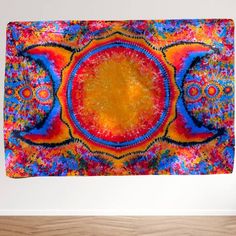 a colorful tapestry hanging on the wall next to a wooden floor in front of a white wall