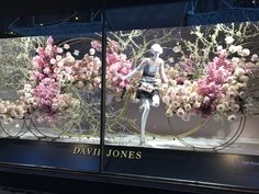 a window display with pink flowers and white mannequins