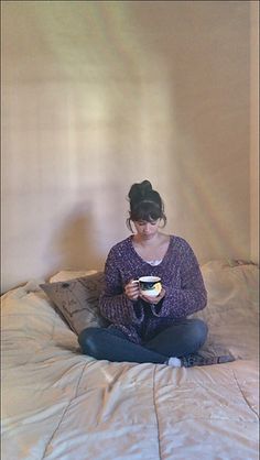 a woman sitting on top of a bed holding a bowl