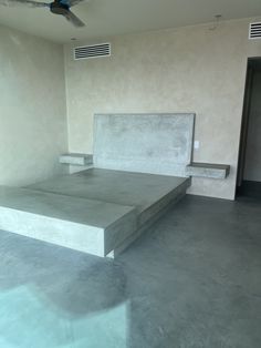 an empty bed room with concrete floors and ceiling fan in the corner on one side