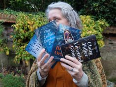 a woman holding up three books in front of her face