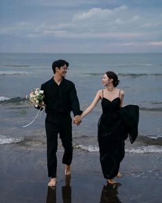 a man and woman holding hands while walking on the beach