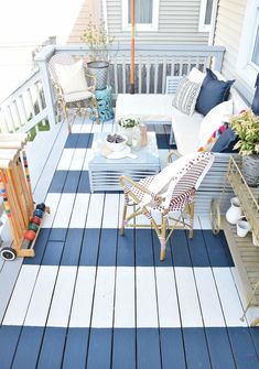 an outdoor deck with blue and white striped rugs, furniture and pillows on it