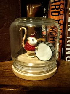 there is a glass jar with a monkey in it on top of a table next to books