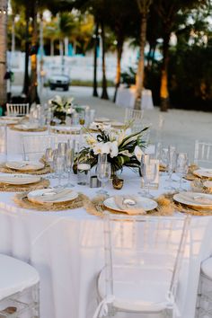 the table is set with white linens and gold place settings