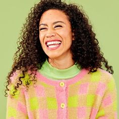 a smiling woman with curly hair wearing a colorful sweater