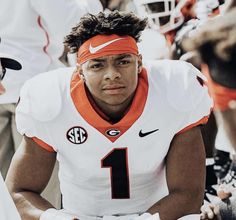 a football player sitting on the sidelines with his headband tied around his face