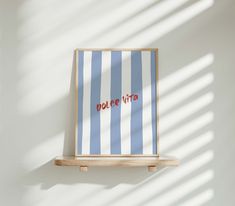 a blue and white striped wall hanging on a wooden shelf with the word dolce vita written in red