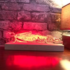 a red lit up race car sitting on top of a wooden table next to a brick wall