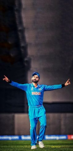 a man standing on top of a green field holding his arms out in the air