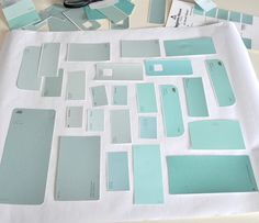 several different shades of blue and green on a table with some white papers next to them